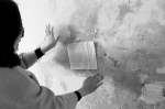 梁女士拿一张面巾纸贴在墙上，很快面巾纸就受潮粘在了墙上。　摄影 孙建一 - 新浪吉林