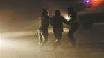武警官兵帮被困者戴上头盔，在飞沙走石中将其引导至装甲车旁。 武警新疆总队克拉玛依支队 供图 - 新浪吉林